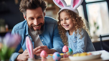 Portrait Of A Man And A Young Child With Bunny Ears, Smiling And Engaging In Easter Festivities, Likely Painting Easter Eggs