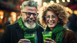Modern adult man and a woman in green glasses drink green traditional beer and joyfully celebrate St. Patrick's Day.