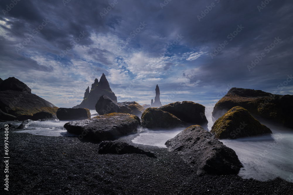 Twilight over an Icelandic black sand beach with moss-covered rocks and ...