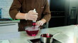 Experienced cook holds syringe disconnecting silicone tube with agar solution to cool down in ice water. Steps crafting jelly dessert