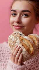 Wall Mural - A beautiful woman is holding bakery bread in the shape of a romantic heart. Valentine's Day food concept