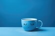 Blue cup with sad facial expression on blue background. Blue monday concept