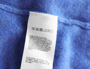 Poster - Clothing label in different languages on blue garment, top view