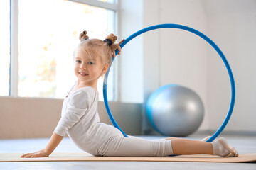 Sticker - Cute little girl doing gymnastics with hula hoop on mat in gym