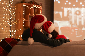 Canvas Print - Young couple watching Christmas movie on projector screen at home, back view