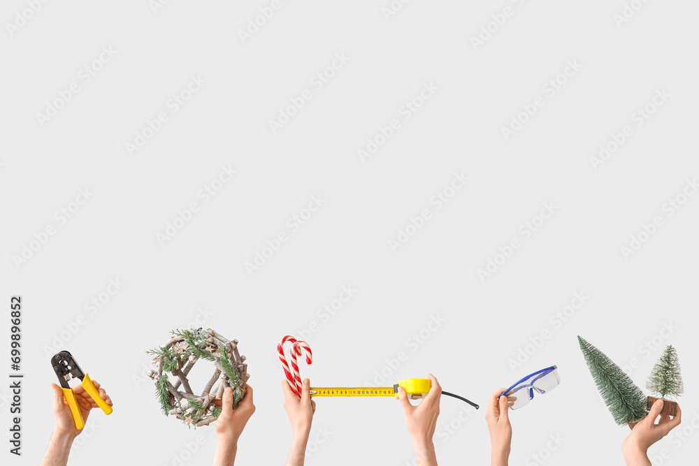 Hands holding construction tools and Christmas decorations on white background