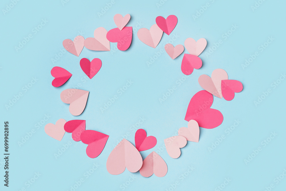 Frame made of pink paper hearts on blue background. Valentine's Day celebration