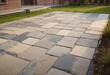 Laying gray concrete paving slabs in house courtyard driveway patio. Professional workers bricklayers are installing new tiles or slabs for driveway, sidewalk or patio on leveled sand foundation base.