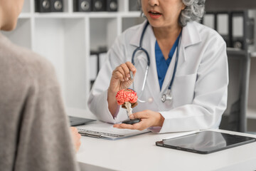 Wall Mural - An elderly Asian doctor is talking to a younger Asian woman across a desk in a medical office, monthly health check appointment.