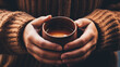 Close up of hands holding steaming hot drink coffee or hot chocolate in a coffee mug 