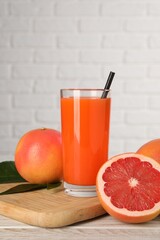 Wall Mural - Tasty grapefruit juice in glass and fresh fruits on light wooden table