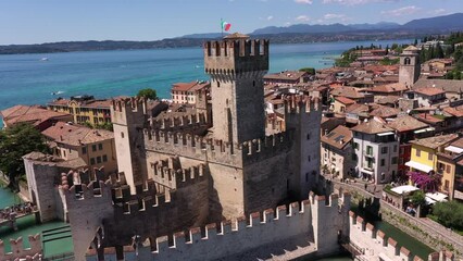 Wall Mural - The historical part of the city of Sirmione on Lake Garda in Italy, slow motion shot by drone. Scaliger Castle of the city of Sirmione 4K video on drone. Sirmione drone view