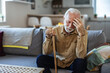 Depressed old man sitting at home while holding walking stick. Retired sad man holding wooden walking cane handle sitting alone at care facility. Elderly man suffering from loneliness and Alzheimer.