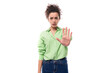 © Ivan Traimak - charming young brunette curly woman with ponytail hairstyle dressed in green shirt shows stop gesture