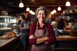 Senior female bakery owner smiling at the camera in front of a camera, in the style of mix of masculine and feminine elements, smooth lines, 