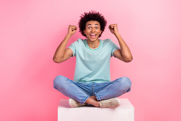 Poster - Full size photo of nice young guy sit white podium raise fists celebration wear trendy blue outfit isolated on pink color background