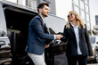 © rh2010 - Female chauffeur greets the businessman while helping him to get out of the minivan taxi. Concept of personal driver, luxury taxi for business people