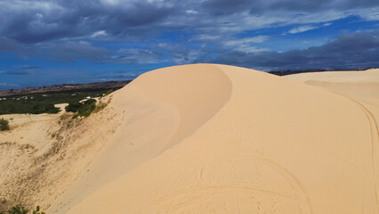 scenic steep large white sand dunes, curved tracks and desert-like landscape with low scrub vegetati