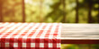 © Gabriela - Checkered tablecloth on wooden table, picnic, forest background. Space for text or advertising