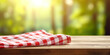 © Gabriela - Checkered picnic napkin on wooden table, forest background, space for text or advertising