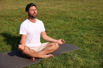 Sticker - Man practicing yoga on mat outdoors, space for text. Lotus pose