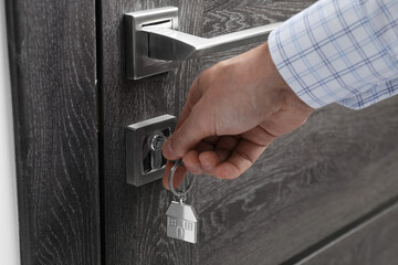 Wall Mural - Man unlocking door with key, closeup view