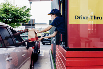 Hand Man in car receiving coffee in drive thru fast food restaurant. Staff serving takeaway order for driver in delivery window. Drive through and takeaway for buy fast food for protect covid19.