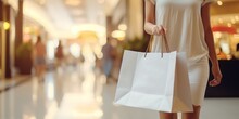 Side view of woman walking and holding big white shopping bag in the shopping center