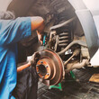 Car mechanic hands replace brakes in garage. Worker changing brake disc in auto repair workshop.