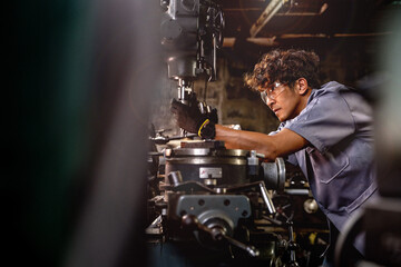 Asian worker in production plant drilling at machine. Professional worker near drilling machine on factory. finishing metal working internal steel surface on lathe grinder machine with flying sparks.