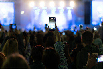 Silhouette of hands using camera phone to take pictures and videos at live concert, smartphone records live music festival, Take photo in front concert stage, happy youth, luxury party.