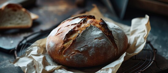 Poster - A loaf of sourdough rye bread wrapped in craft paper Fresh bread is cooled on a special metal wire rack. Creative Banner. Copyspace image