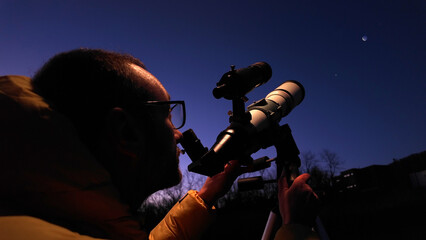 Wall Mural - amateur astronomer looking at the evening skies, observing planets, stars, moon and other celestial 