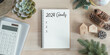 2024 goals new year resolutions on blank note book memo reminder wish list of yearly planner, action plan for work-life balance, good financial health, happy home family, travel aims on office desk