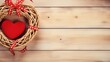 A packed gift, a rattan heart wreath and a red ribbon with hearts in a close up. Light wooden background. St. Valentines, anniversary, wedding concept with copy space. Space for your text