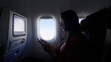 Fototapeta  - Caucasian female passenger chatting online via cellphone using wifi internet connection on board. Young woman browsing network during flight
