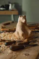 Poster - The master woodcarver begins work on the bear figure by carving it out of wood