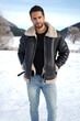 Captivating winter fashion shot featuring a handsome brown man donning a stylish black vest with fur collar. 