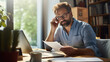 © Studio Nova - Focused man working on a laptop and reading a document.