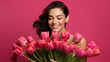 © Studio Nova - Woman peeking out from behind a large bouquet of pink tulips, with her eyes smiling and the rest of her face playfully hidden by the flowers.