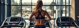 Fototapeta  - Back of woman running on a treadmill in a gym.