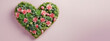 flat flay view of a wreath of beautiful spring blooming green cactus in the shape of a heart on minimal light pink vivid colored background