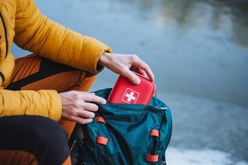 a guy puts a first aid kit in a backpack, packing things for a hike, safety in a winter trip, trekki