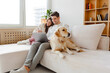 © Maria Vitkovska - Happy young couple using laptop, man holding mobile phone, hugging dog. Online shopping concept