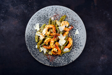 Wall Mural - Traditional fried king prawns with Italian foglie di olivo pasta and parmesan cheese served as top view on a design plate with text space