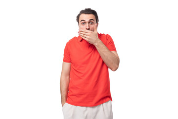 Canvas Print - young brunette man in a red corporate t-shirt on a white background with copy space