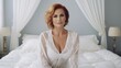 © Mickael - Very attractive mature women posing sitting at her bedroom looking at the camera.Attractive middle aged lady in nightdress lying on bed. Generative AI