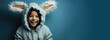 © brajianni - Horizontal banner with copyspace for text. Joyful cheerful child smiling and laughing in hooded jacket with bunny ears on blue background. Concept for children's holiday, egg hunt, happy easter, joy