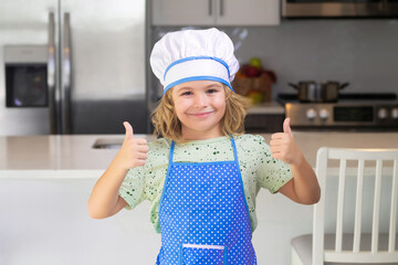 Wall Mural - Portrait of funny child chef in kitchen. Funny child stand at kitchen table have fun baking, doing bakery preparing food at home kithen.