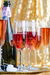 Wall Mural - glasses of rose champagne on sparkling golden cloth